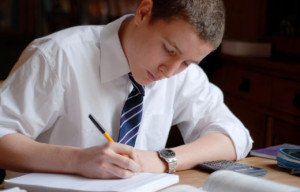 joven-con-corbata-estudiando-escribiendo-sobre-un-cuaderno